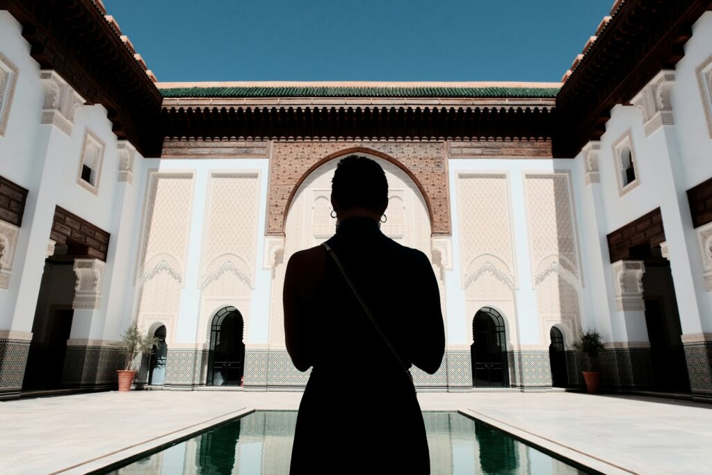 man in black coat standing near white concrete building during daytime,morocco travel guide