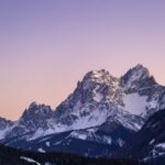 Snow-capped mountains against a colorful sky.