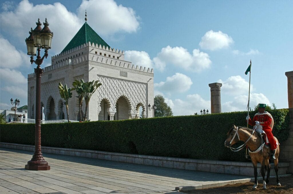 Royal guard on horseback at the Mausoleum of Mohammed V in Rabat under a bright blue sky.