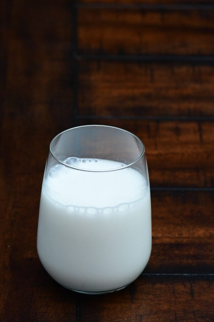 clear drinking glass with white liquid, goat with milk