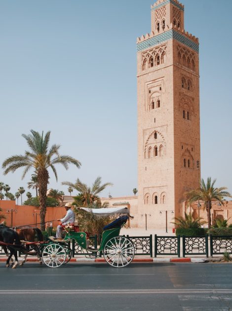a horse drawn carriage in front of a tall tower, what to wear in morocco