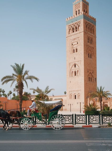 a horse drawn carriage in front of a tall tower, what to wear in morocco
