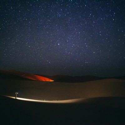 a person standing in the middle of a desert at night