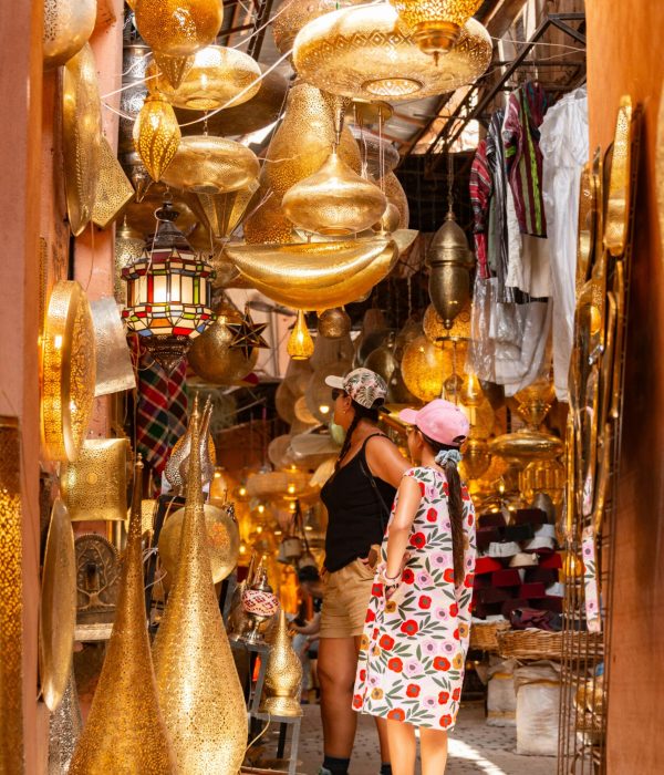 Morocco Family Tours 1 A mother and daughter explore a vibrant Moroccan market filled with golden lamps.morocco family tours