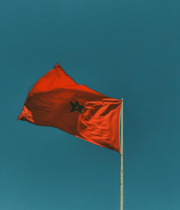 Marokko: Oplev det Fængslende Nordafrika – Kultur, Klima og Historie 1 Red Moroccan flag waving against a blue sky, symbolizing national pride.marokko