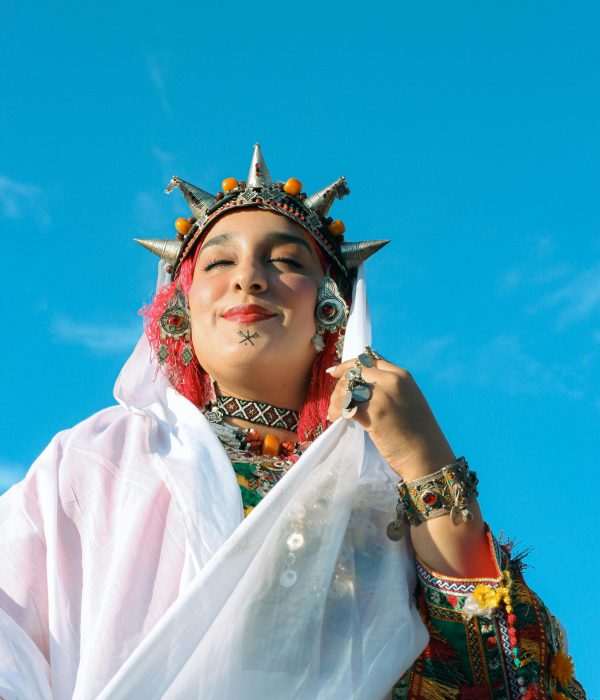 Moroccan People: A Deep Dive into Morocco’s Rich Culture and Heritage 2 A woman in colorful traditional Berber clothing under a clear blue sky in Morocco.moroccan people