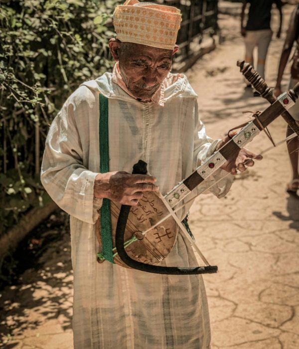 Moroccan Musical Instruments: A Guide to Morocco’s Traditional Sounds 1 Elderly man in Morocco plays the traditional string instrument Sintir, showcasing cultural heritage.moroccan musical instruments