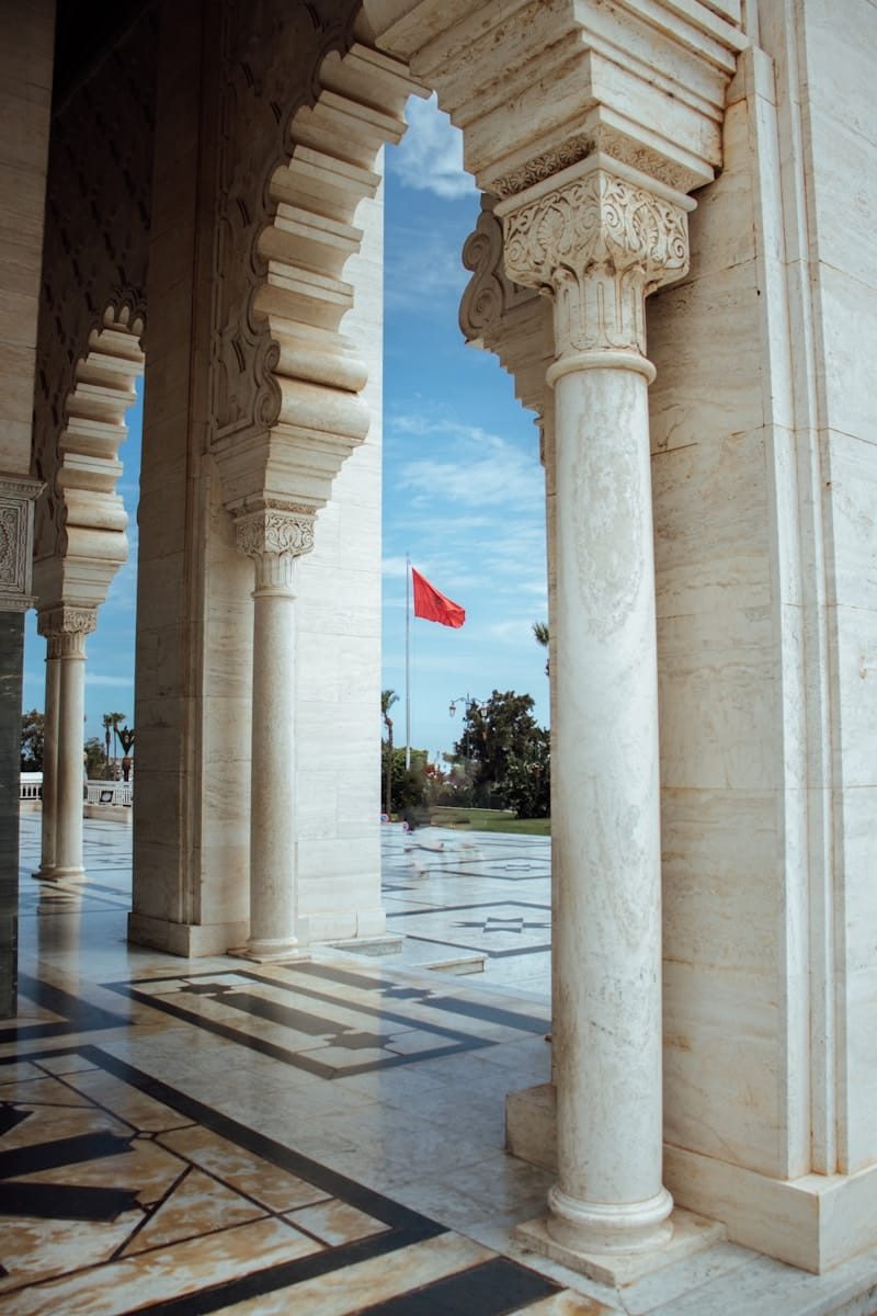 Ornate columns frame a view of a red flag.Rabat North Africa