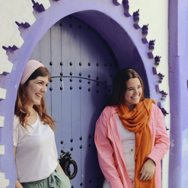 two women standing in front of a purple door