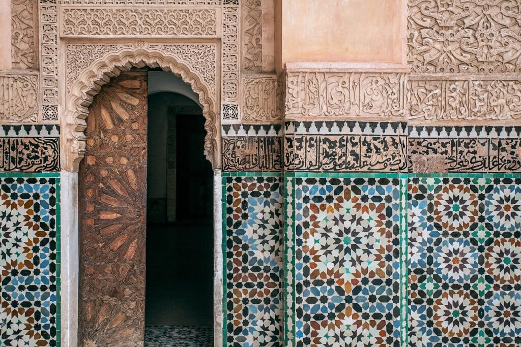 Aged house exterior with arched entrance door and geometric decor on stone walls in city in daylight.Weather in June in Morocco