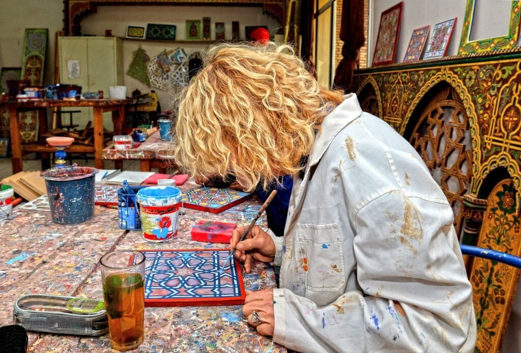 Artist focuses on creating a vibrant traditional Moroccan pattern in Fès workshop.weather in morocco in april