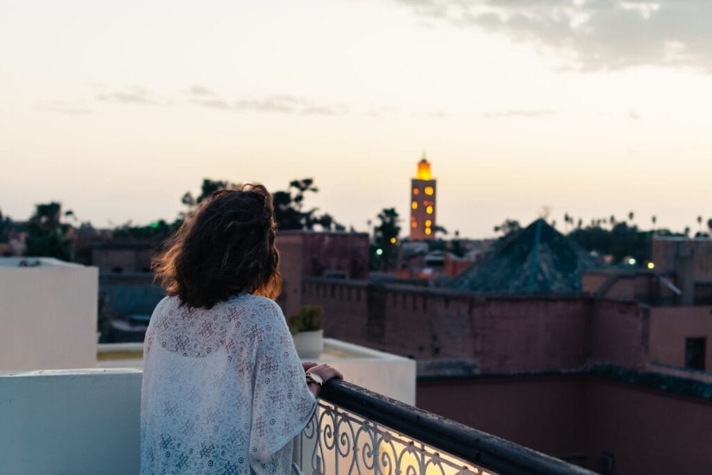 A woman gazes at the evening skyline of Marrakech, appreciating the sunset from her hotel balcony.Morocco in May weather