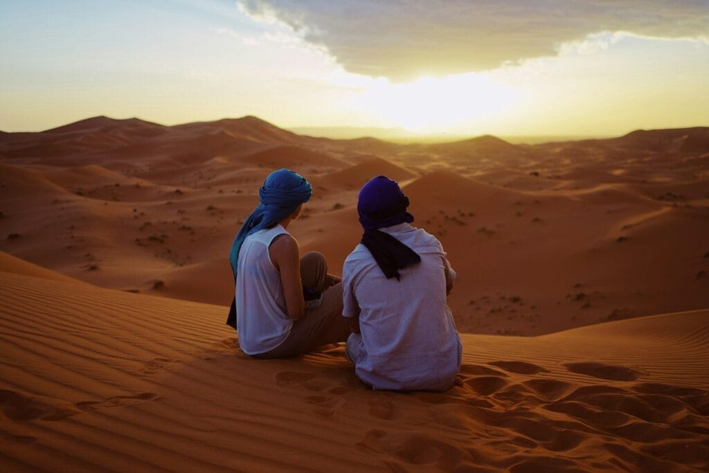 two men sitting on sand dunes.people of Morocco