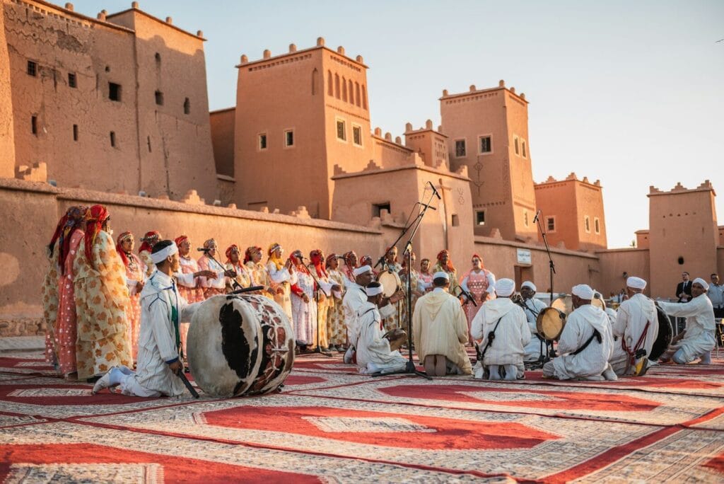 a group of people standing on top of a rug.Weather in Morocco in July