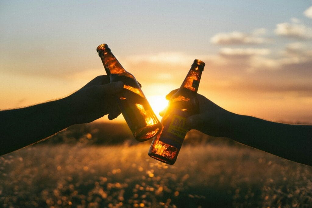 photography of person holding glass bottles during sunset.alcohol in morocco